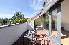 Dachterrasse mit zwei Liegestühlen, Glasschiebetüren und Blick auf Bäume und Hügel.