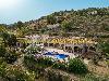 Villa in Spanien mit Terrakotta-Dachziegeln, Swimmingpool und Terrassen zwischen Olivenbäumen auf einem bewaldeten Hang.