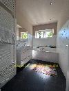Badezimmer mit weiße Wandfliesen, eine Badewanne, einen Waschtischunterschrank, ein Fenster und einen bunten Teppich.