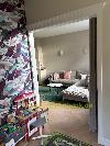 Durch eine Türöffnung ist ein Wohnzimmer mit grauem Ecksofa und grünem Teppich sichtbar.