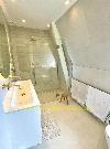 Badezimmer unter einer Dachschräge mit Glasdusche, weißem Waschtischunterschrank und Handtuchheizkörper.