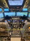 Das Cockpit zeigt zwei Pilotensitze, beleuchtete Bedienfelder und gelbe Markierungen auf dem Boden von Landungs Bahn vor der Frontscheibe.