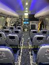 Flugzeugkabine mit Reihen blauer Passagiersitze, einem Mittelgang, Gepäckfächern und blauer Deckenbeleuchtung.