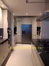 Moderne Küche mit einem zentral platzierten Kühlschrank mit zwei Türen, weißen Schränken und schwarzen Arbeitsplatten.