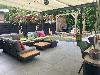 Überdachte Terrasse mit modularen Loungesofas, niedrigen Holztischen, Pflanzgefäßen und einer Holzpergola.