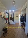 Flur mit einer Holztreppe, einem runden Spiegel, einer Garderobe mit Jacken und einer Blumenvase.