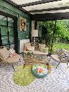 Sitzbereich mit einem beigefarbenen Sofa, zwei Sesseln, einer Glaswand und Blick auf einen grünen Garten.